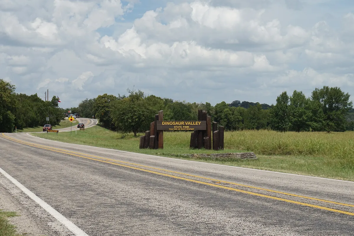 Two-lane FM 205 curving past the Dinosaur Valley State Park entrance near Glen Rose, Texas