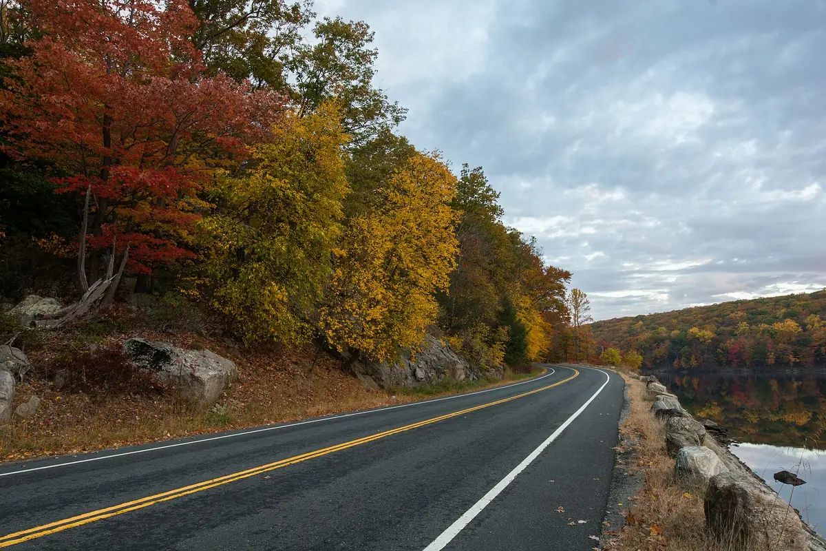 Seven Lakes Drive curving along Lake Askoti under fall foliage in Harriman State Park